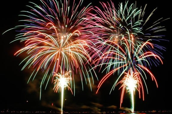 Colorful fireworks bursting over a dark night sky and water.