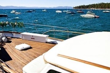 View from a boat deck on a lake, with many boats in the water and trees on the horizon.