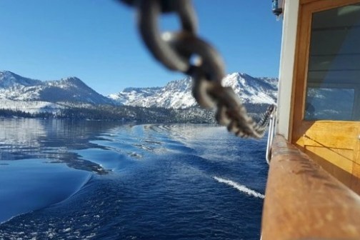 Boat sailing on a lake with snowy mountains in the background.