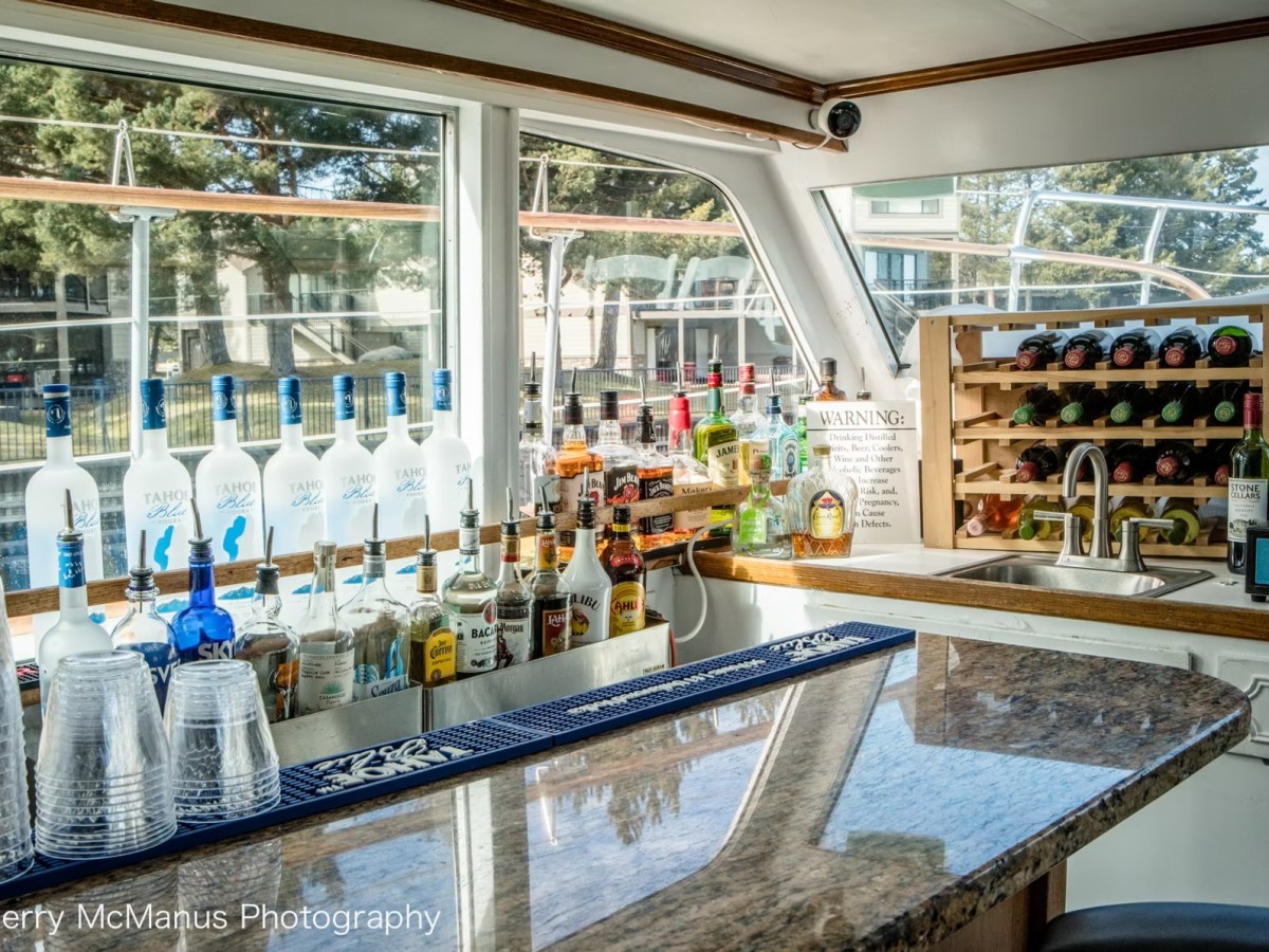 Boat bar with liquor bottles, wine rack, and glasses on counter.